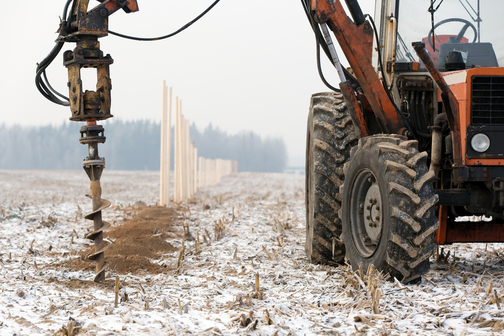 boring holes in ground with drilling rig during fence construction